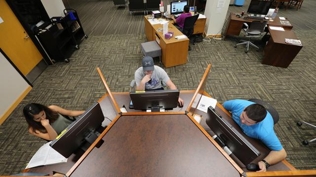 Aerial view of students working at an octagonal computer station in the library