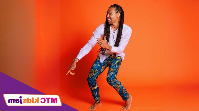 Pierce Freelon smiles and dances in front of a bright orange background.